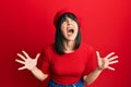 Young hispanic woman wearing french look with beret crazy and mad shouting and yelling with aggressive expression and arms raised Royalty Free Stock Photo