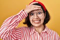 Young hispanic woman wearing glasses over yellow background stressed and frustrated with hand on head, surprised and angry face Royalty Free Stock Photo