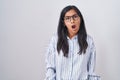 Young hispanic woman wearing glasses in shock face, looking skeptical and sarcastic, surprised with open mouth Royalty Free Stock Photo