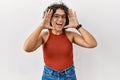 Young hispanic woman wearing glasses standing over isolated background smiling cheerful playing peek a boo with hands showing face