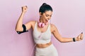 Young hispanic woman wearing gym clothes and using headphones dancing happy and cheerful, smiling moving casual and confident Royalty Free Stock Photo