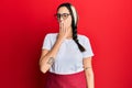 Young hispanic woman wearing professional waitress apron bored yawning tired covering mouth with hand