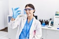 Young hispanic woman wearing scientist uniform holding pill at laboratory Royalty Free Stock Photo