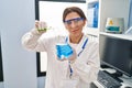 Young hispanic woman wearing scientist uniform measuring liquid at laboratory Royalty Free Stock Photo