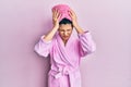 Young hispanic woman wearing shower towel cap and bathrobe suffering from headache desperate and stressed because pain and Royalty Free Stock Photo