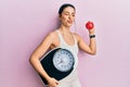 Young hispanic woman wearing sportswear holding weighing machine and apple looking at the camera blowing a kiss being lovely and Royalty Free Stock Photo
