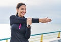 Young hispanic woman wearing sportswear stretching arms at seaside Royalty Free Stock Photo