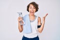 Young hispanic woman wearing sportswear and towel drinking bottle of water celebrating victory with happy smile and winner Royalty Free Stock Photo