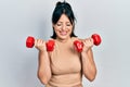 Young hispanic woman wearing sportswear using dumbbells smiling and laughing hard out loud because funny crazy joke Royalty Free Stock Photo