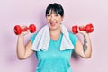 Young hispanic woman wearing sportswear using dumbbells smiling and laughing hard out loud because funny crazy joke Royalty Free Stock Photo