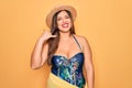 Young hispanic woman wearing summer hat and swimsuit over yellow background smiling doing phone gesture with hand and fingers like Royalty Free Stock Photo