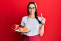 Young hispanic woman wearing waitress apron holding tray with breakfast smiling with an idea or question pointing finger with Royalty Free Stock Photo