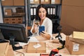 Young hispanic woman working drinking wine and using smartphone celebrating crazy and amazed for success with open eyes screaming Royalty Free Stock Photo