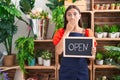 Young hispanic woman working at florist holding open sign covering mouth with hand, shocked and afraid for mistake Royalty Free Stock Photo