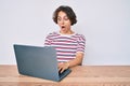 Young hispanic woman working at the office with laptop scared and amazed with open mouth for surprise, disbelief face Royalty Free Stock Photo