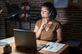 Young hispanic woman working at the office at night thinking concentrated about doubt with finger on chin and looking up wondering Royalty Free Stock Photo