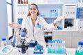 Young hispanic woman working at scientist laboratory looking at the camera smiling with open arms for hug Royalty Free Stock Photo