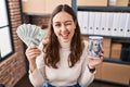 Young hispanic woman working at small business ecommerce holding money and piggy bank winking looking at the camera with sexy Royalty Free Stock Photo