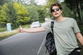 young hitchhiker in sunglasses stopping car