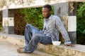 Young homeless African man with plastic bowl looking hungry Royalty Free Stock Photo
