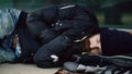 Young homeless drunk man trying to sleep on cardboard on bench at the sidewalk Royalty Free Stock Photo