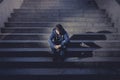 Young homeless man lost in depression sitting on ground street concrete stairs Royalty Free Stock Photo