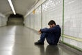 Young homeless man lost in depression sitting on ground street subway tunnel