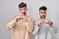 Young homosexual couple standing over white background rejection expression crossing fingers doing negative sign Royalty Free Stock Photo