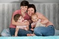 A young homosexual lesbian couple with two children at home, on the bed.