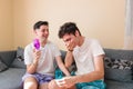 Latino gay couple toasting and laughing with wine glasses in their living room, celebrating anniversary Royalty Free Stock Photo