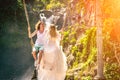 Young honeymoon couple swings in the jungle near the lake, Bali island, Indonesia.