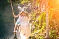 Young honeymoon couple swings in the jungle near the lake, Bali island, Indonesia.