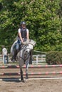 Young horsewoman with back protector is jumping