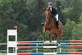 Young horsewoman in black jacket is jumping