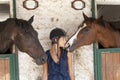 Young horsewoman with its horses in the stable Royalty Free Stock Photo