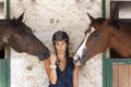 Young horsewoman with its horses in the stable Royalty Free Stock Photo