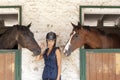 Young horsewoman with its horses in the stable Royalty Free Stock Photo