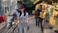 Young horsewomen lead a horses by the bridles to walk.