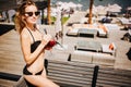 Young hot woman resting alone. Attractive beautiful girl posing on camera in swinsuit and cocktails in hands. Slim well
