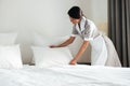 Young hotel maid setting up pillow on bed Royalty Free Stock Photo