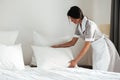 Young hotel maid setting up pillow on bed Royalty Free Stock Photo