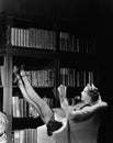 Young housekeeper reading a book while reclining in a library armchair