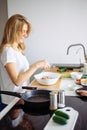 Caucasian blonde woman cooking marinade for tasty kebabs at kitchen table Royalty Free Stock Photo