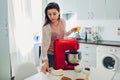 Young housewife cooking pie according to recipe in culinary book. Woman using food processor on kitchen Royalty Free Stock Photo