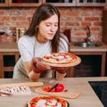 Young housewife cooking pizza at her kitchen