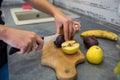 Young housewife cutting  fruits on wooden board while making healthy food for breakfest Royalty Free Stock Photo