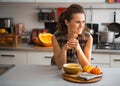 Young housewife eating pumpkin soup in kitchen Royalty Free Stock Photo