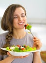 Young housewife enjoying eating greek salad