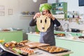 Young housewife having fun holding funny dough face while baking pastry in the kitchen