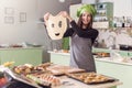 Young housewife having fun holding funny dough face while baking pastry in the kitchen